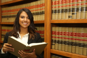 A paralegal stands by a law book case examining a text